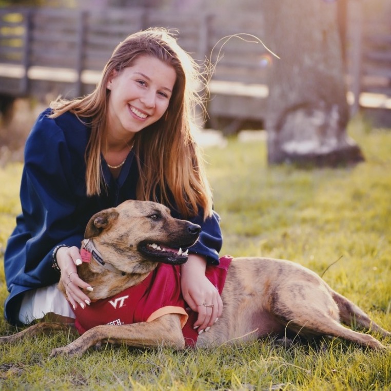 Girl and Brown Dog Sitting in Grass while Both Smile